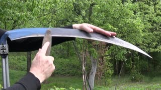 scythe sickle -with-stone-in-spring-farm-